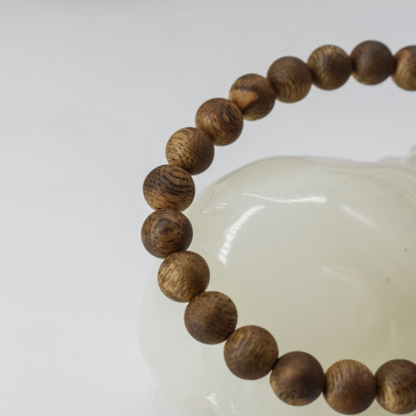 Close-up of 6mm Hainan Green Qinan agarwood beads with natural grain variation